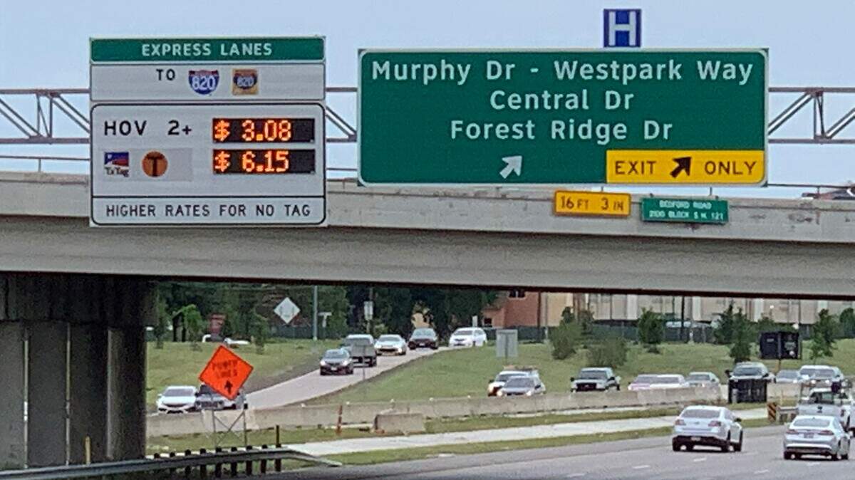Motorists drive past a TEXPress lanes sign advertising tolls for $6.15 for a 5.7-mile trip.